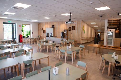 Förskolematsal med små bord och stolar i ljusgrönt.